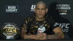 Alex Pereira at a UFC 320 press conference with the UFC light heavyweight championship belt on the table