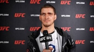 Movsar Evloev speaks into a UFC microphone during a post-fight interview in front of a UFC backdrop
